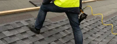 A roofing contractor installs new shingles on a residential roof